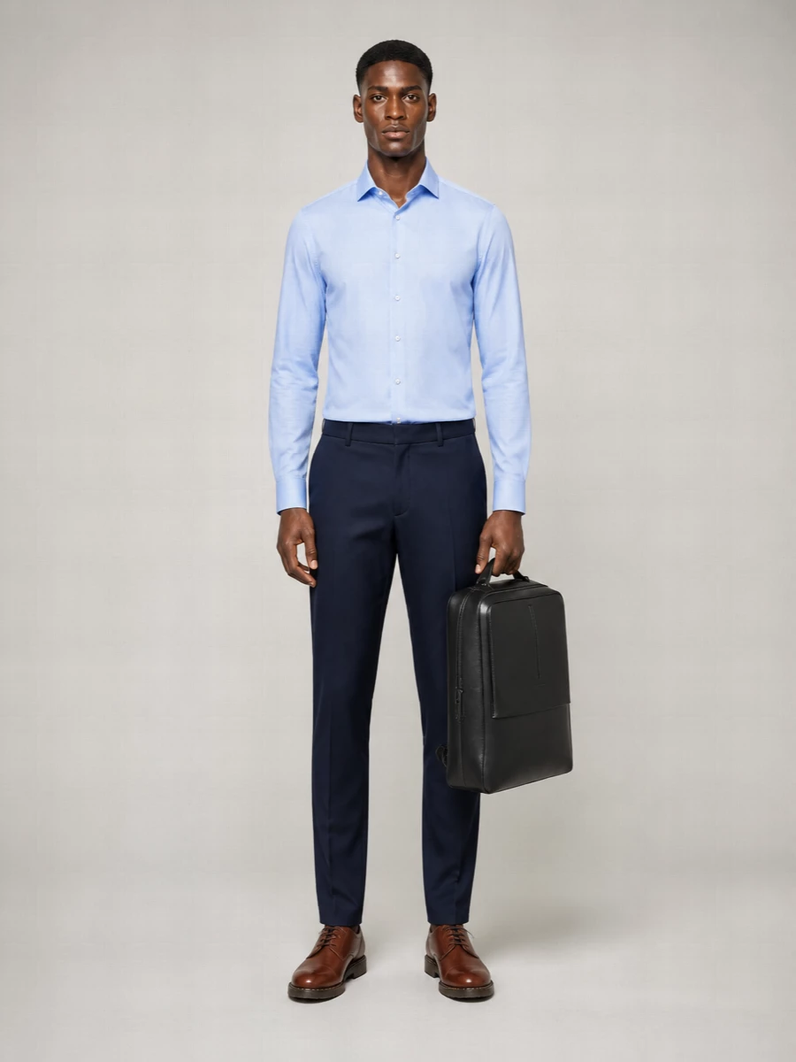 A crisp light blue shirt meets slim navy trousers for a clean, modern take on business preppy. Chestnut derbies warm up the blues, while the structured black work bag keeps the whole ensemble office sharp yet easy to wear all day.