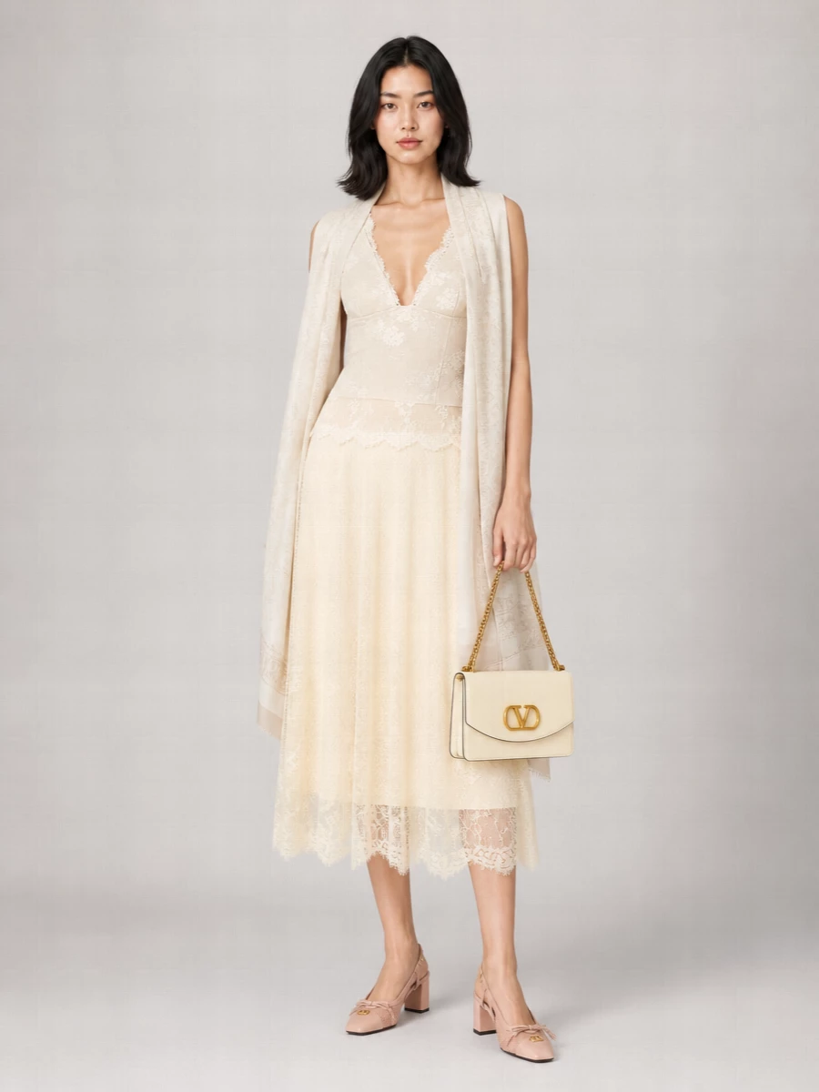 A romantic study in ivory and buttercream, this outfit lets the lace camisole and matching lace midi skirt create a soft, elongated line that feels intimate yet polished. Blush nude block-heel slingbacks and a structured buttercream bag keep the palette gentle and cohesive, adding just enough structure to balance the delicacy. The result is quietly luxurious summer occasion dressing, perfect for garden cocktails or intimate dinners where you want softness with real intention.