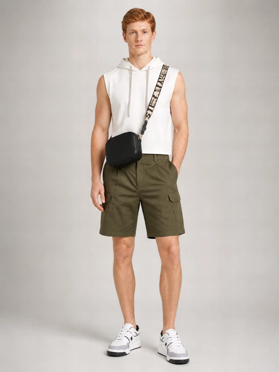 Soft white on top with olive utility shorts keeps the palette grounded and the silhouette sharp, cropped and relaxed where it counts. Chunky Valentino sneakers pick up the monochrome of the hoodie, so the whole thing reads clean but still low-key graphic. The compact crossbody finishes it with just enough structure to feel considered without interrupting the ease.
