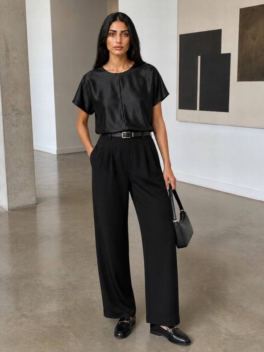 An all‑black column in fluid tailoring, grounded by a satin top, reads calm and precise rather than severe. Gold‑touched loafers and a slim belt introduce structure and subtle shine, while the compact shoulder bag keeps everything close to the body for a clean, modern finish.