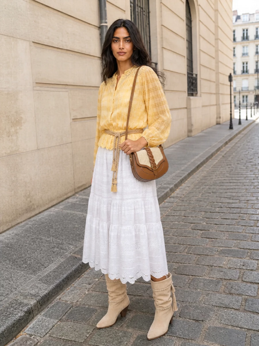 Sunlit lemon and soft white lace come together in a romantic, head-to-toe Isabel Marant moment that feels airy yet considered. The tiered midi and slouchy suede boots balance volume and length, keeping it relaxed but polished enough for summer dinners or garden parties. A tan and raffia saddle bag and braided rope belt quietly tie in warm tones and texture for a cohesive boho finish.