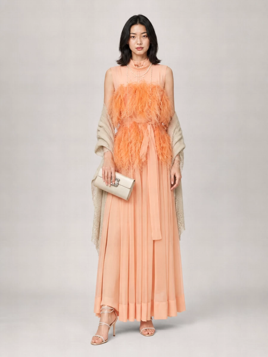 A couture-leaning peach feather gown is anchored with champagne crystal sandals and a luminous satin clutch, keeping the palette soft and elongated from shoulder to toe. Pearls and warm gold add a gentle glow at the neckline, reading intimate and romantic rather than showy. The result is a formal evening ensemble that feels cinematic yet whisper-soft in colour and movement.