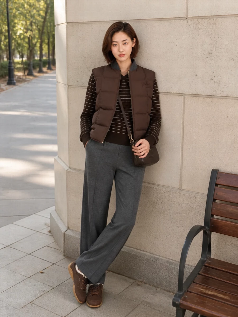 I’m taking the track-pant route rather than a dress so the padded Miu Miu gilet can stay the anchor of a true off-duty city uniform. The striped knit, wool-look track pant and shearling-lined sneakers sit in the same brown and charcoal story, so the volume reads intentional rather than heavy. The compact crossbody keeps everything grounded and practical, ready for cold urban days that still feel considered.