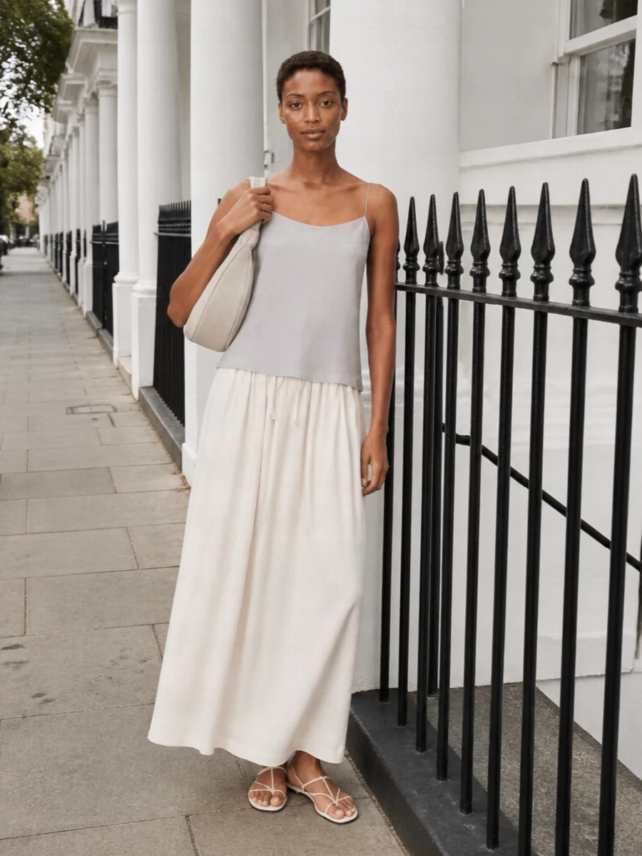 A softly tonal summer pairing that lets the grey cami skim into an ivory maxi, creating a long, fluid line with almost no seams to interrupt it. Barely there ivory sandals and a sculpted shoulder bag keep everything light and precise, while a gauzy scarf adds just enough texture to feel considered but still very relaxed.