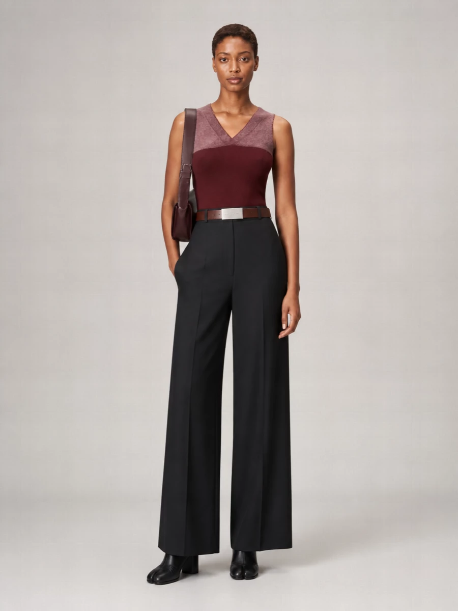 A deep burgundy Margiela knit meets razor-clean black wide-leg tailoring for a column that feels thoughtful rather than severe. Black split-toe boots and a structured oxblood shoulder bag keep the mood precise and cohesive, with the high waist and subtle belt detailing giving just enough definition to the long line.