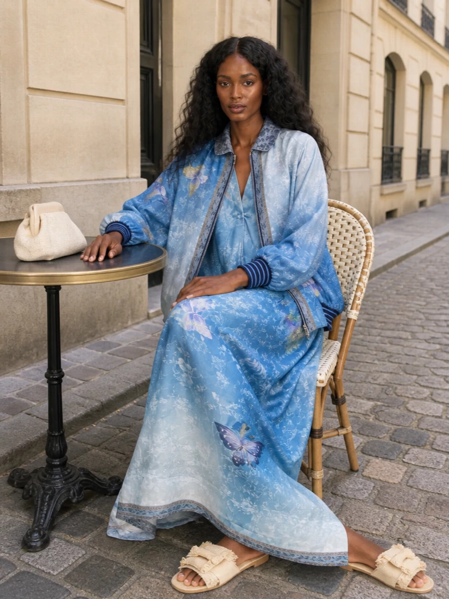 I’m building this around the bomber and its dreamy butterfly print, so the matching kimono maxi dress is the most harmonious anchor, turning the layers into a single, watery sky of pattern. Flat raffia slides keep the mood romantic and bohemian but grounded for day, while the structured neutral clutch adds just enough polish and calm to balance all that movement and print. The result is a soft, destination-ready ensemble that feels intentional rather than busy, with the outerwear and dress reading like one collectible Pierre Louise Mascia story.