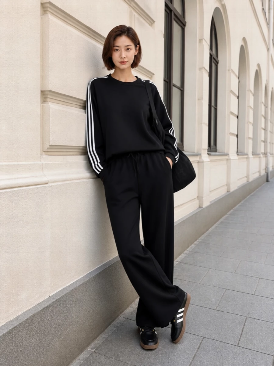 A monochrome Y-3 track set lets the Adidas slip-ons feel intentional rather than casual, keeping the stripes and gum sole as the only real contrast. The boxy sweatshirt and wide-leg pant create a long, relaxed line that is still sharp enough for city errands or travel, with the technical shoulder bag reinforcing the clean, sport-driven story. Choosing separates over a dress keeps this rooted in athletic styling, so the sneaker’s heritage details read as a deliberate design choice, not an afterthought.