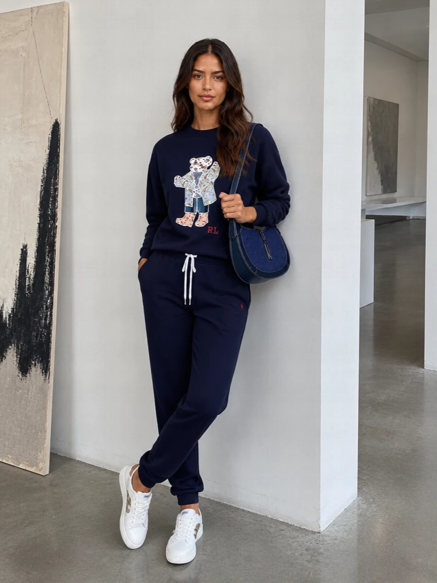 Head-to-toe navy keeps the Polo Bear front and centre, reading relaxed yet intentional for coffee runs, flights or slow weekends in the city. The joggers echo the sweatshirt’s easy volume, while refined sneakers and a structured crescent bag sharpen the set just enough for stepping outside without changing a thing.