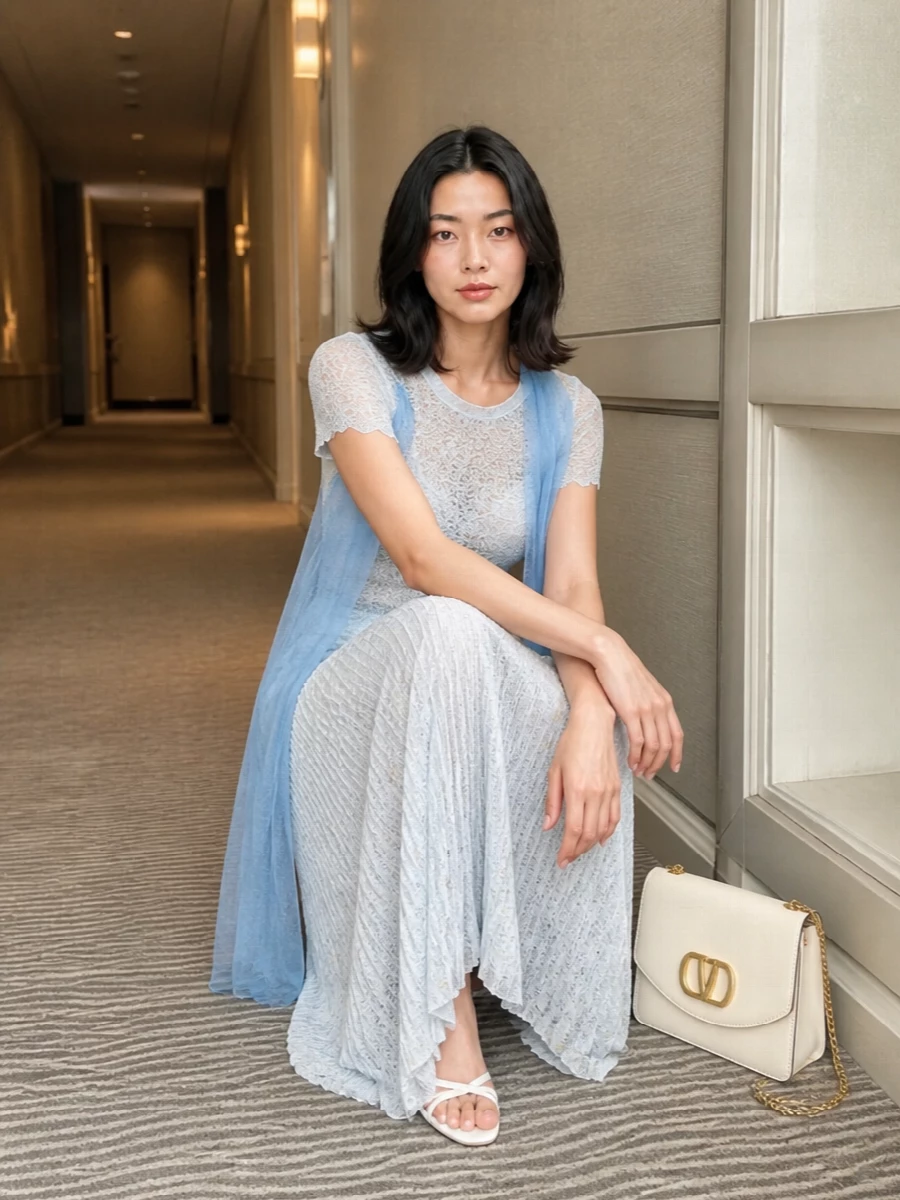 A whisper of icy blue and soft white runs through this pairing, turning the pleated maxi into a fluid, monochrome column of lace and light. Minimal white stilettos and a structured buttercream shoulder bag sharpen the romance just enough, so the outfit feels poised for garden weddings, terrace lunches or late summer dinners without ever reading fussy.