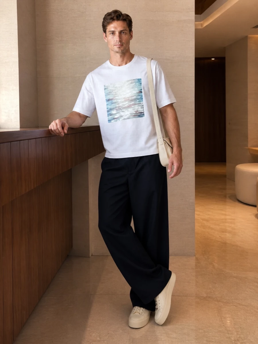 A soft white water-print tee meets deep navy wide-leg trousers for a calm, gallery-in-the-city mood. Creamy sneakers and a pale shoulder bag keep the story light and tonal, so the interest comes from shape and movement rather than contrast.