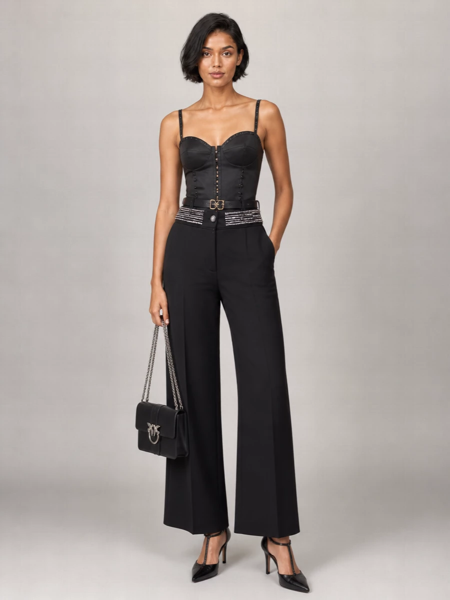 A sharp black-and-silver evening ensemble that leans into the trousers’ crystal waist with a sculpted corset top and precise, leg-lengthening heels. The proportions stay clean and long, with all the interest focused at the waist and shoulders. A structured chain-detailed bag and discreet belt finish it with Italian night-out polish that still feels modern and graphic.