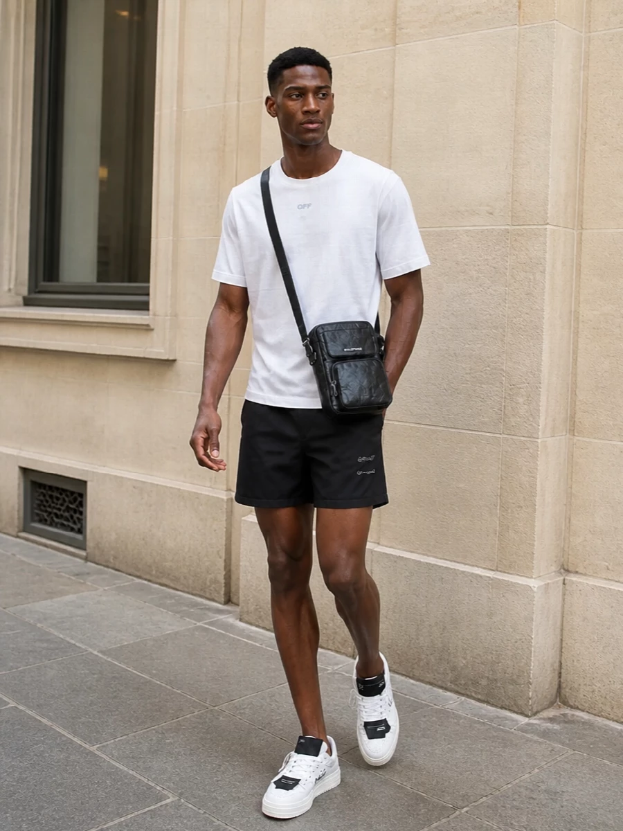 This look leans into a crisp monochrome street-sport story: black Off-White swim shorts grounded by a relaxed white Off-White tee and clean white logo sneakers. The proportions stay easy and regular, so it reads effortless from poolside to city, while the subtle branding and compact crossbody keep the outfit elevated without feeling loud.