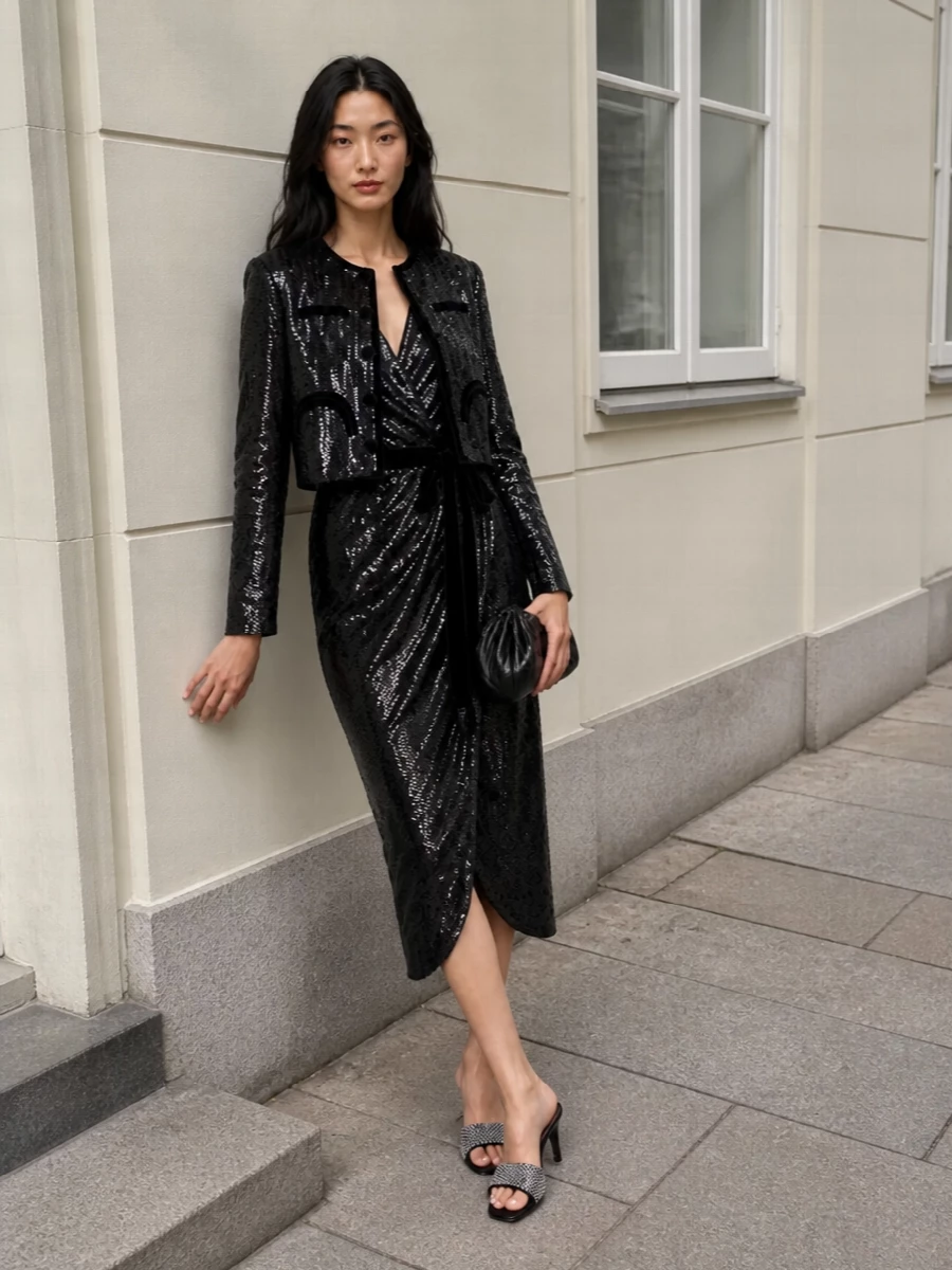 I am treating the sequin Blazé Milano jacket as the hero and building around it with a single, fluid anchor rather than competing tailoring. The Alberta Ferretti wrap midi in black paillettes continues the black and gunmetal story in a softer line, so the cropped, couture-feel jacket can sit cleanly over the shoulders without fighting lapels or waistbands. Crystal-detailed Attico mules and a gunmetal Themoiré clutch keep the sparkle graphic and directional, giving you a sharp, modern evening ensemble that reads rich and considered rather than over-styled.