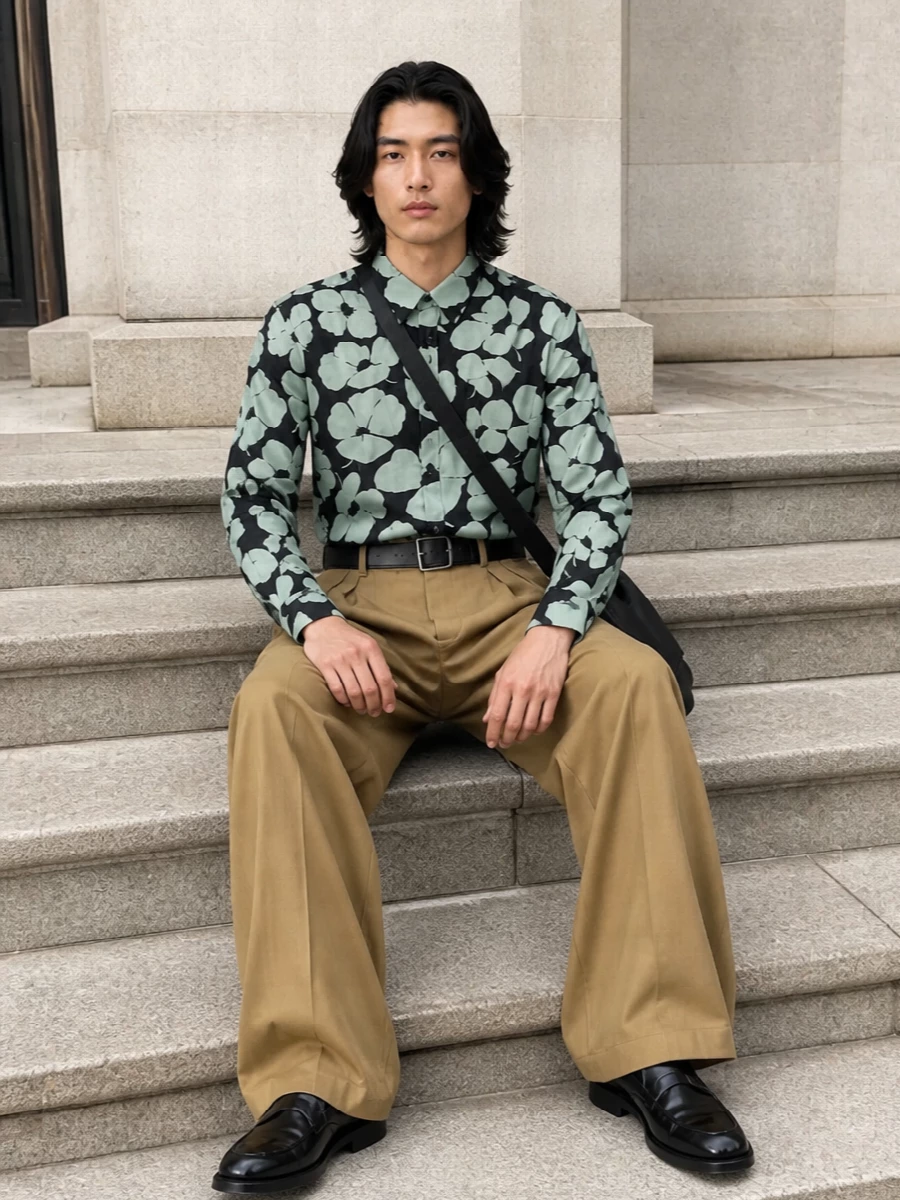 A graphic Dries floral shirt softens into high-rise camel tailoring, the wide leg giving the print room to breathe while keeping the mood refined. Polished black derbies and a clean leather crossbody ground the volume, so the romance reads confident rather than precious. It is an art-aware summer outfit that moves easily from gallery afternoons to dinner terraces.