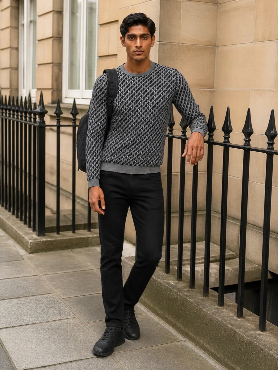 Emporio Armani’s geometric knit sits on a foundation of black slim denim, giving the pattern room to breathe while keeping the silhouette lean and modern. All-black runners continue the minimal, street-aware line, and a structured black backpack ties the monochrome base together for a quietly branded city uniform. The result is relaxed enough for weekend movement yet polished enough for low-key evenings out.