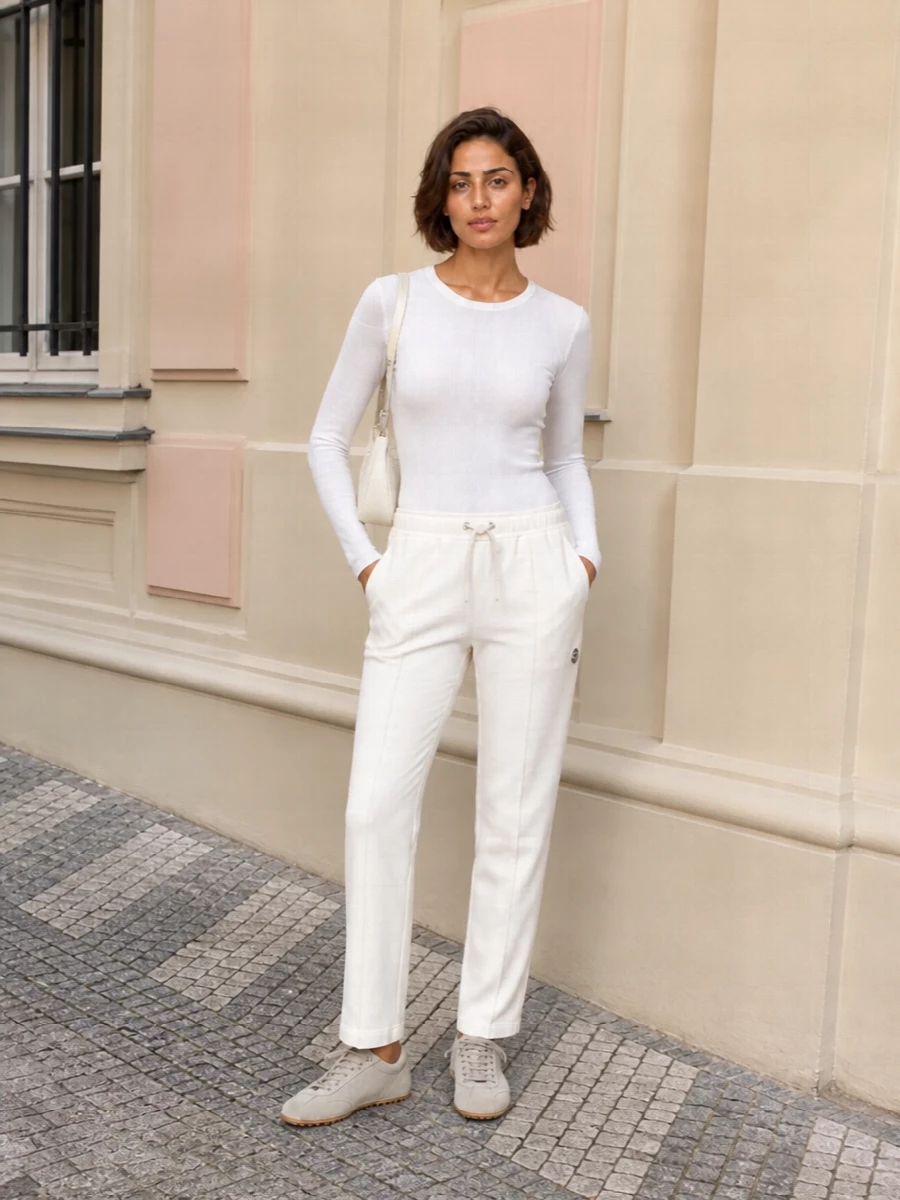 Moncler’s off white track pant meets a sheer-sleeved Sportmax knit for a crisp, streamlined take on sport that still feels thoughtfully put together. Tod’s suede sneakers keep the energy relaxed yet polished, while the sculpted Paco Rabanne baguette introduces a subtle architectural edge in the same light neutral palette. The result is a quietly luxurious, city-ready set that moves easily from travel days to low-key dinners without ever feeling overtly athletic.