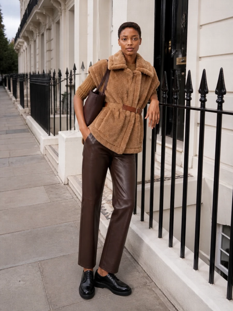 I’m building around the teddy vest as outerwear, so a knit top and tailored bottom feel more resolved than adding another dress layer underneath. The cropped camel jumper and coated chocolate trouser create a clean, modern column under the cocoon, with black derbies and a deep brown bucket bag sharpening the softness into something city ready and quietly assured.