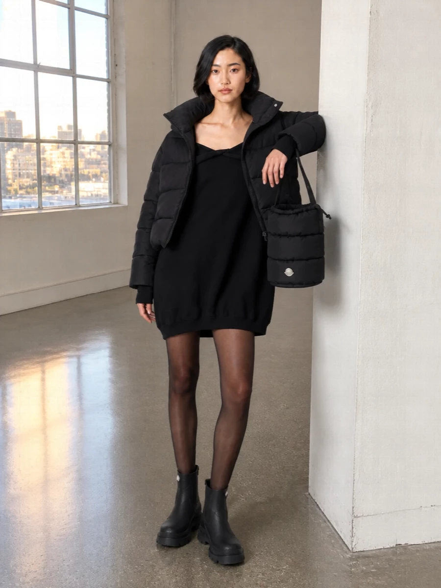 I’m taking the dress path here, because a single, slouchy knit base under the cropped Pinko puffer keeps the line clean and lets the outerwear stay the focus. The Mm6 off-shoulder mini gives that slightly undone streetwear attitude, while the Moncler lug boots and padded bucket bag lock it into a cold-weather, city-ready register. All-black, graphic textures and a short hem against solid boots keep it modern, confident and properly winter-proof without feeling heavy.