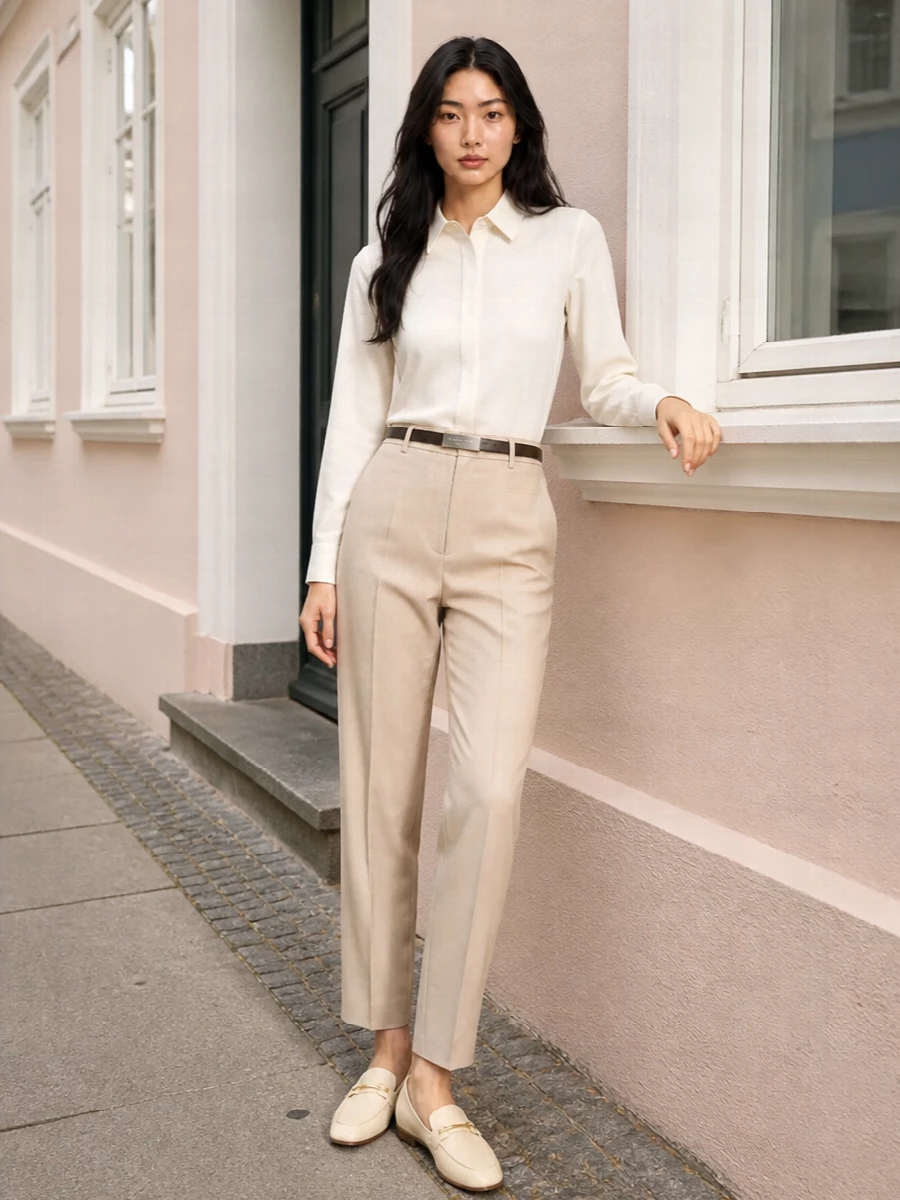 A quietly precise palette of ivory and light beige lets the tailored lines do all the work, from the crisp shirt to the elongated trouser. The slim belt and taupe top-handle add just enough structure and contrast to keep the silhouette sharp without disturbing the soft neutrals. This is warm-weather boardroom dressing that reads calm, controlled and considered from every angle.