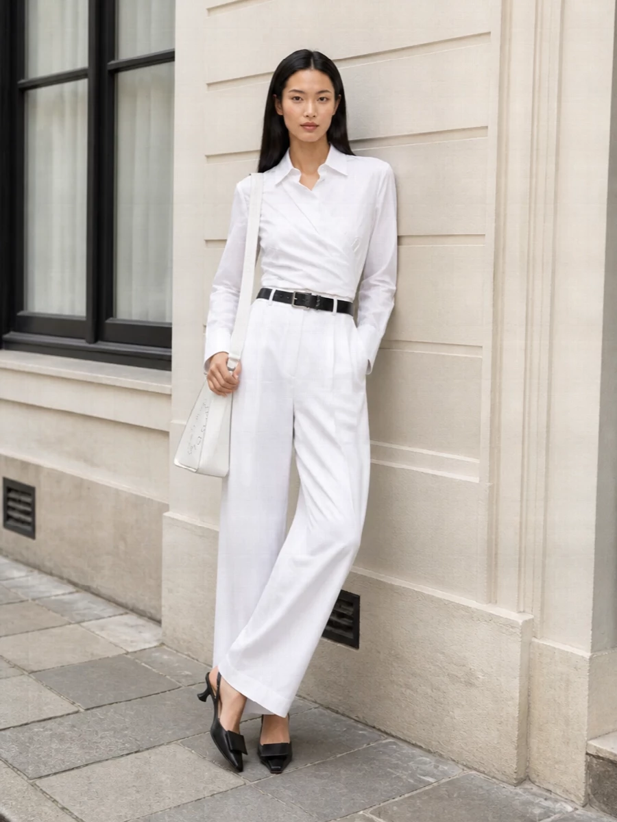 This look is a study in clean, sculpted summer tailoring: high-waisted white Sportmax trousers paired with the wrapped white shirt create a long, cinched silhouette that feels both sharp and softly feminine. Jacquemus’s low-heel slingbacks and a structured white Stella McCartney shoulder bag keep the palette luminous and the attitude quietly confident, while the slim Saint Laurent belt adds just enough definition to pull the whole ensemble into precise, city-ready polish.