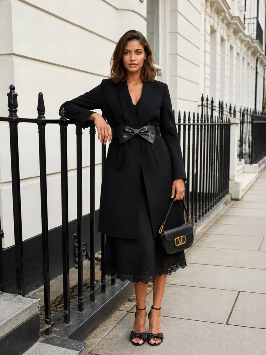 This is a pure Valentino evening ensemble built around the sculpted black bow coat and a clean black lace-hem midi dress. The bow-strap sandals and compact gold‑logo bag pick up the leather bow detailing without adding noise, keeping the line long, romantic and restrained. I chose the dress path over separates to let the coat’s architecture and bow be the central statement, with everything else reading as quiet, precise support.