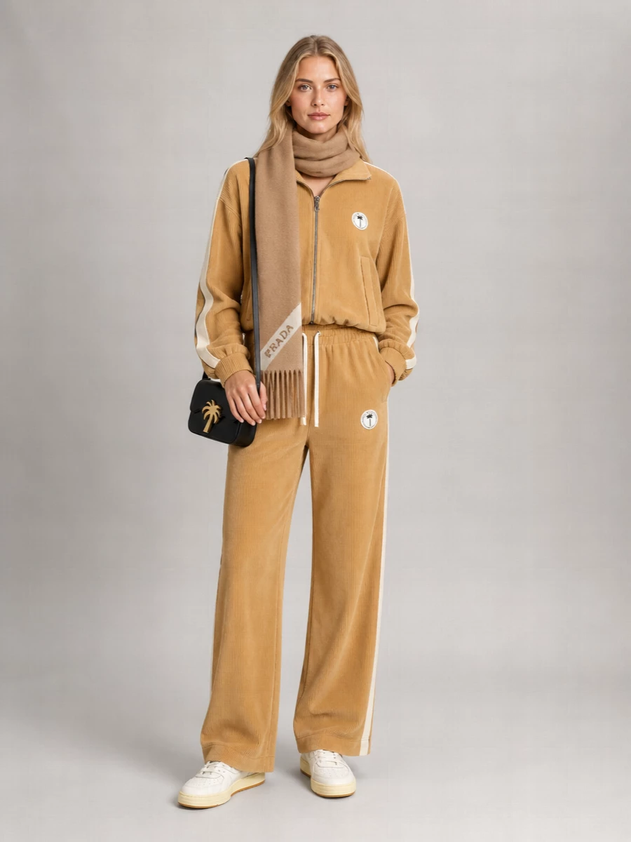 Camel corduroy takes center stage here, with the matching Palm Angels track jacket and wide-leg pant reading like a relaxed, city-ready set. Off white sneakers and a black logo cross-body keep it grounded and graphic, while the camel scarf adds just enough texture for colder days without disturbing the clean, sporty lines.