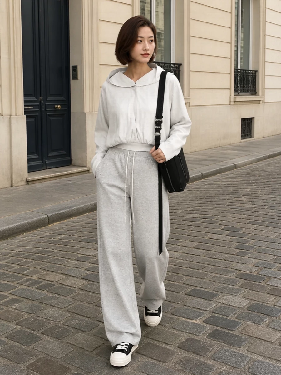 Light heather-grey wide-leg sweats are grounded with a cropped off-white DRKSHDW blouson, creating an elongated, off-duty Rick column that still feels intentional. Black platform DRKSHDW sneakers and a structured black Loewe crossbody sharpen the palette and pull the look into a streamlined, city-ready uniform that’s relaxed but distinctly high fashion.