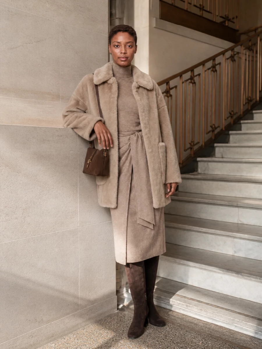 I chose the dress path to keep the silhouette long and uncluttered, letting the faux-fur coat remain the tactile focal point over a clean knit column. The taupe Max Mara wrap dress, dark chocolate knee boots and slim brown cross-body sit in a warm, tonal spectrum that feels calm, discreet and city-ready. It is a softly structured winter ensemble that moves easily from daytime appointments to dinner without a change of base.