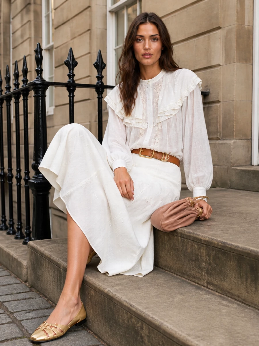 Soft ivory on ivory keeps the story calm, letting the blouse’s lace and the skirt’s embroidery quietly play against each other. A cinched tan waist, blush clutch and gold-detailed flats bring just enough structure and shine for long lunches, terraces and warm city evenings. The result is romantic Chloé ease that still feels considered and polished from every angle.