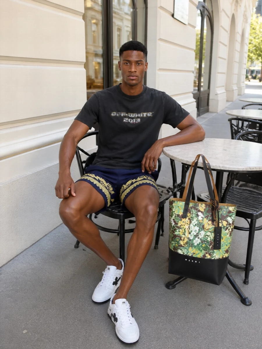 Navy and gold Versace swim shorts sit against a washed black Off-White tee for a pool-to-city mix that feels graphic but controlled. White and black Off-White courts keep the line sporty and crisp, while the structured Marni floral tote brings that final hit of designer irreverence you actually want at a beach club. It is relaxed, logo-driven and unapologetically high-end without tipping into costume.