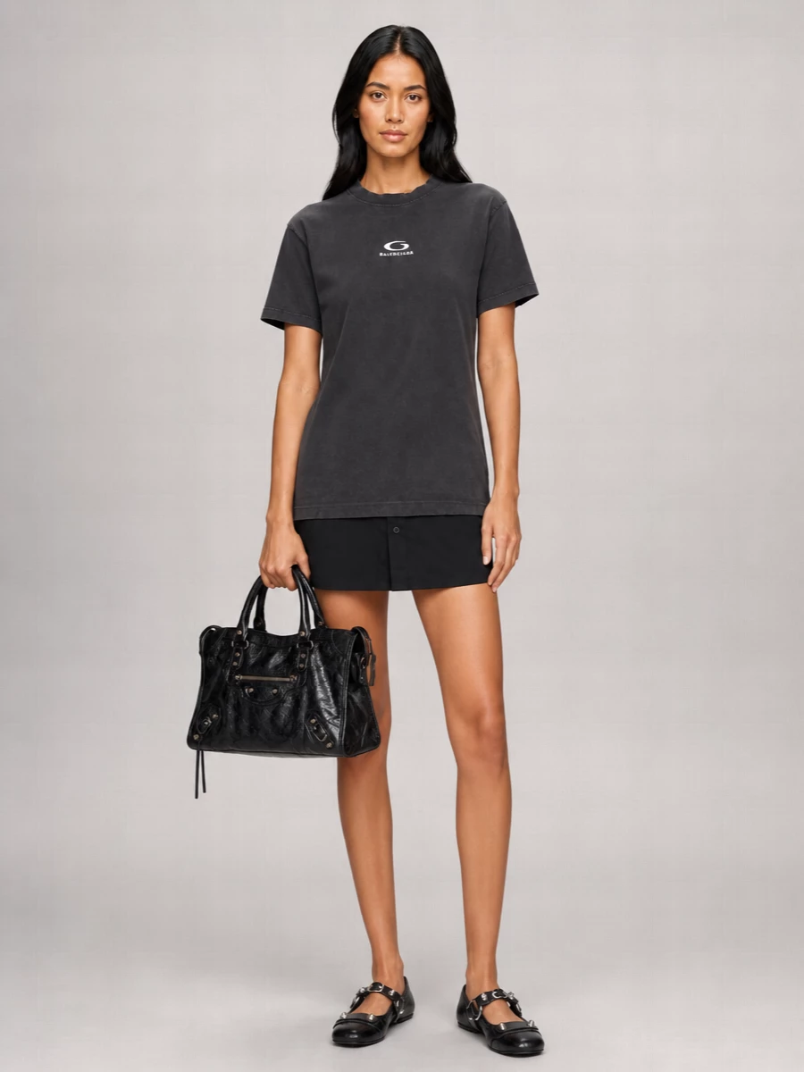 This one leans into the graphic street side of Balenciaga rather than going down the dressy evening route. The faded layered T-shirt mini and hardware ballerinas echo the City bag’s crinkled leather and studs, keeping everything dark, irreverent and easy to wear from daytime pavement to late-night bar hop. It is a tight, logo-inflected uniform that feels collectible without trying too hard.