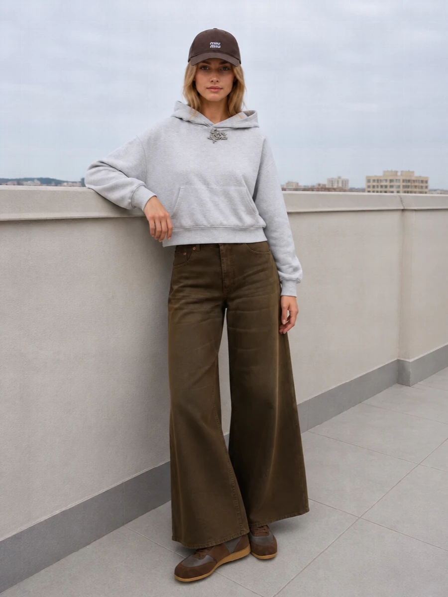This is a grounded, logo-aware streetwear edit built around warm browns and soft greys. The cropped hoodie and wide-leg denim play with proportion in a way that feels relaxed but sharply considered, while the tonal sneakers and structured bag keep the palette tight and quietly luxurious. I chose the top and trouser route over a dress so the cap reads as part of a laid back city uniform rather than an afterthought accessory.