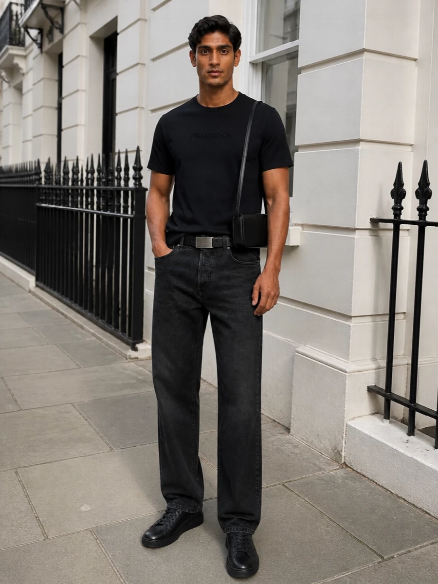 A deep black JW Anderson tee sits over washed‑black straight jeans for a clean, logo‑light take on city dressing. All‑black Y‑3 sneakers keep the line sleek and grounded, while a compact Jacquemus shoulder bag and a slim Margiela belt introduce discreet structure and hardware. The result is a monochrome uniform that feels modern, quiet and distinctly designer without trying too hard.