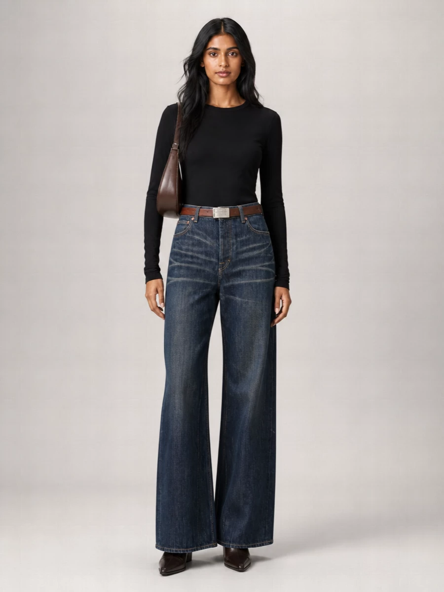 A pared back black knit top lets the pinstriped wide-leg denim read as the main gesture, sharp but relaxed. Dark brown square-toe boots and a sculpted leather shoulder bag add depth without breaking the quiet palette. A barely-there reversible belt finishes the waist cleanly, so the whole outfit feels composed yet easy for city days and low key evenings.