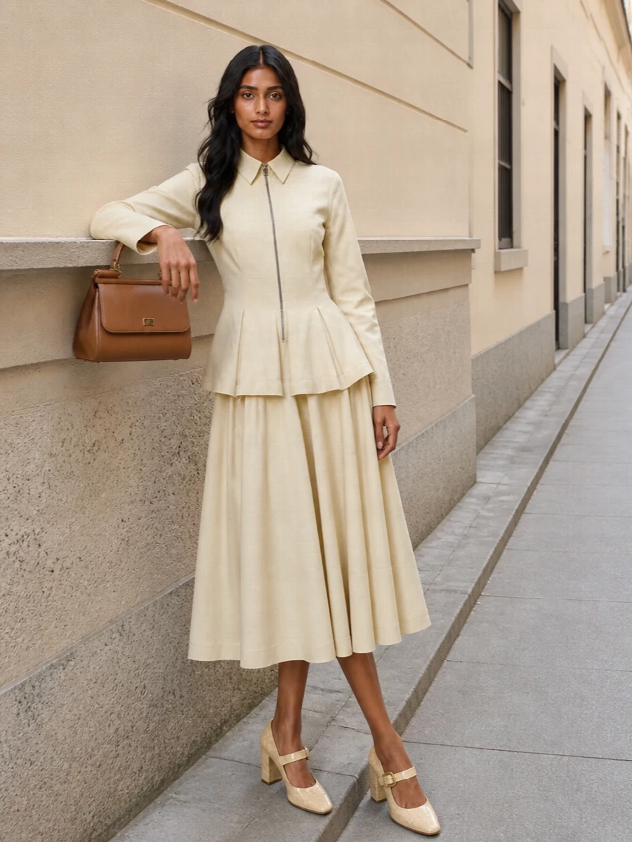 A buttercream Bottega Veneta midi and the camel Dolce&Gabbana satchel create a quietly sculpted neutral story, all clean structure and soft volume. The architectural peplum and pleated skirt keep the silhouette precise yet fluid, while the croc-embossed Mary Jane in matching tones and gold hardware ties the whole ensemble into a refined, dinner-ready finish. Opting for the dress route keeps the eye on proportion and texture, rather than breaking the line with separates.
