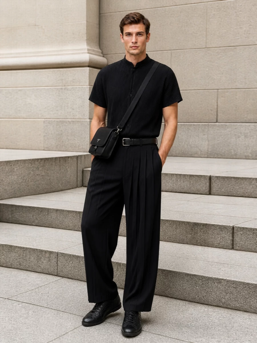 A fully pleated black column on top and bottom creates a precise, sculptural line that feels minimal yet expressive. Low-profile black leather sneakers keep it grounded and modern, while a structured crossbody and slim belt introduce just enough hardware to underline the quiet, tailored polish. It is gallery-ready dressing that balances comfort with a distinctly architectural presence.