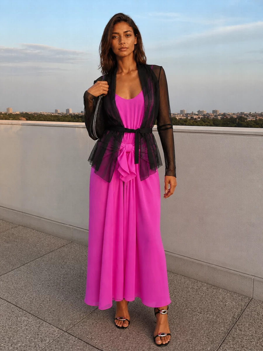 Hot pink takes the lead, with inky black accessories grounding the draped maxi into something sharp and night-ready. Sleek, hardware-detailed sandals and a crystal-swept shoulder bag keep it modern and slightly subversive while staying firmly in cocktail territory. The result feels polished, directional, and built around that single, sculptural shot of color.