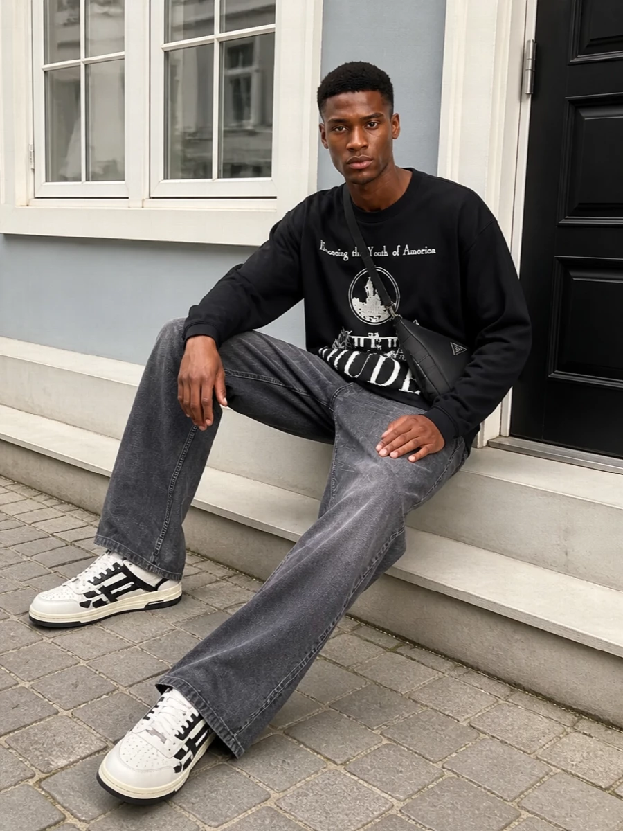 A graphic Rhude crew sits over loose charcoal Rick denim for a laid back, West Coast street uniform that feels easy but intentional. Off white and black Amiri courts echo the tee’s print, while a sharp Prada crossbody keeps essentials close without breaking the monochrome flow.