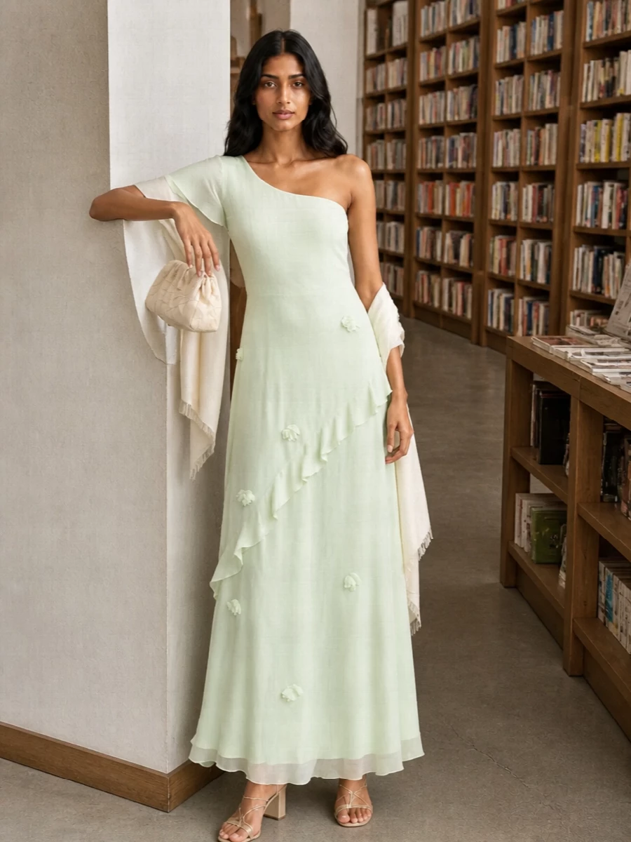 A pale mint one shoulder is paired with champagne straps and buttercream accessories for a soft, luminous take on garden party dressing. Metallic touches stay diffused and subtle, letting the gauzy movement and floral appliqué of the dress stay in focus. The result feels romantic and modern, perfect for outdoor weddings or coastal evenings where you want polish without heaviness.