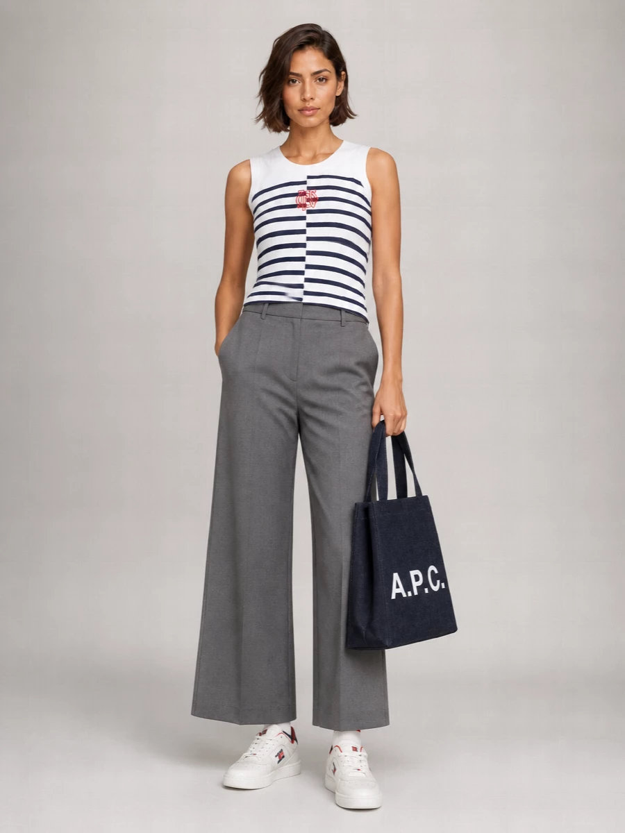 Gaultier’s split-stripe tank meets precise grey wide-leg tailoring for a fresh, nautical-meets-city take that feels sharp but relaxed. Clean white court sneakers and an inky structured tote keep it grounded and wearable from coffee runs to casual dinners. Striped sport socks peeking between trouser hem and sneaker give a small, deliberate nod back to the tank’s graphic lines.