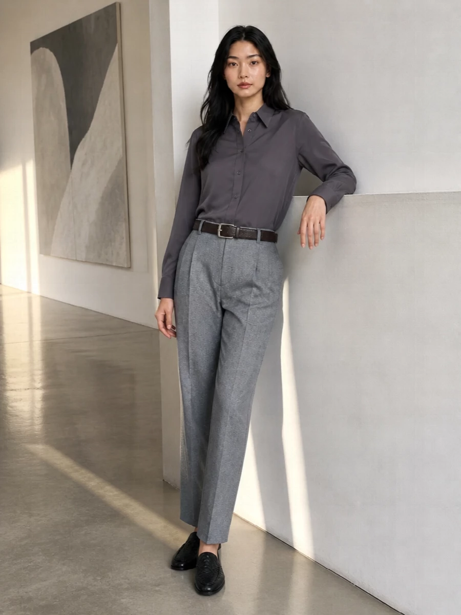Charcoal and grey are handled with precision here, the longline shirt and high-rise trouser creating a lean, tailored column that feels quietly assured for serious city days. Black leather accessories and a deep espresso bag introduce depth without noise, keeping every line clean and every detail considered. It is office dressing that prioritises ease of movement and subtle structure over overt statement.