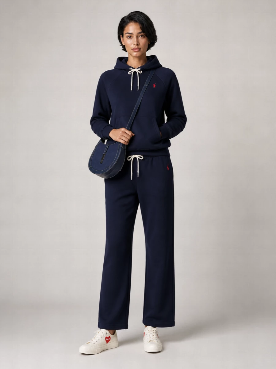 A head-to-toe navy Ralph Lauren knit set keeps the mood calm and collegiate, with the straight leg giving a cleaner line than classic joggers. Off-white sneakers and a compact navy cross-body sharpen the palette just enough for coffee runs, travel days or easy campus weekends.