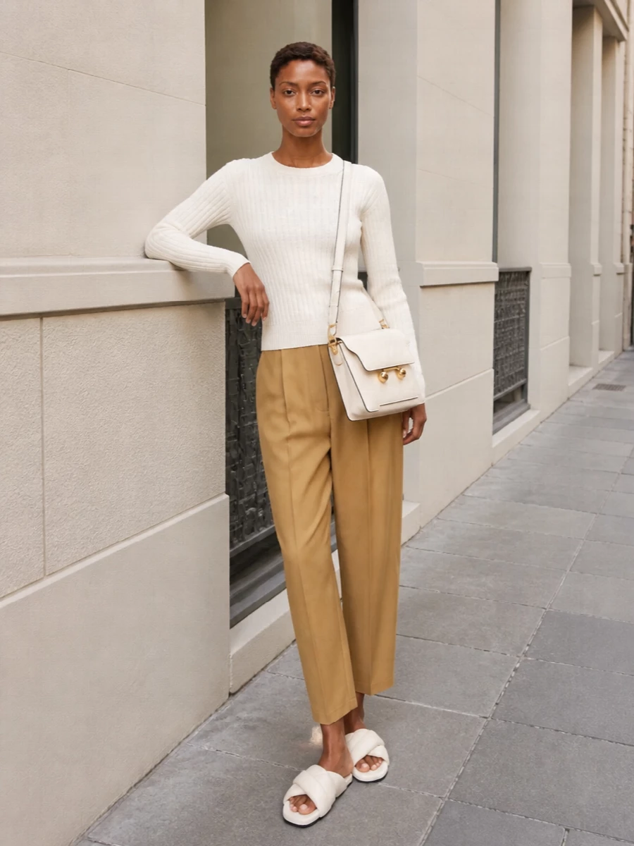 Marni’s ribbed ivory knit meets sculpted camel tailoring for a quiet, intelligent take on everyday dressing. The high-rise pleated trouser and padded ivory slides create an easy long line that still feels precise. A cream structured shoulder bag keeps everything in the same soft, thoughtful palette, adding just enough structure to feel considered without reading formal.