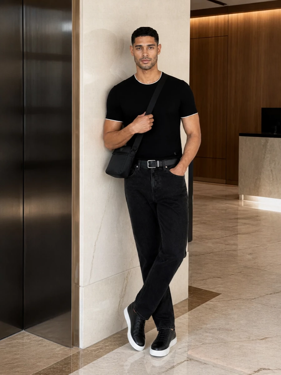 Washed-black straight jeans, a tipped black tee and grained black leather sneakers create a monochrome city uniform that reads clean, modern and quietly confident. The compact crossbody and precise belt keep the lines sharp, so the outfit shifts easily from daytime roaming to low-key dinners without needing a change.