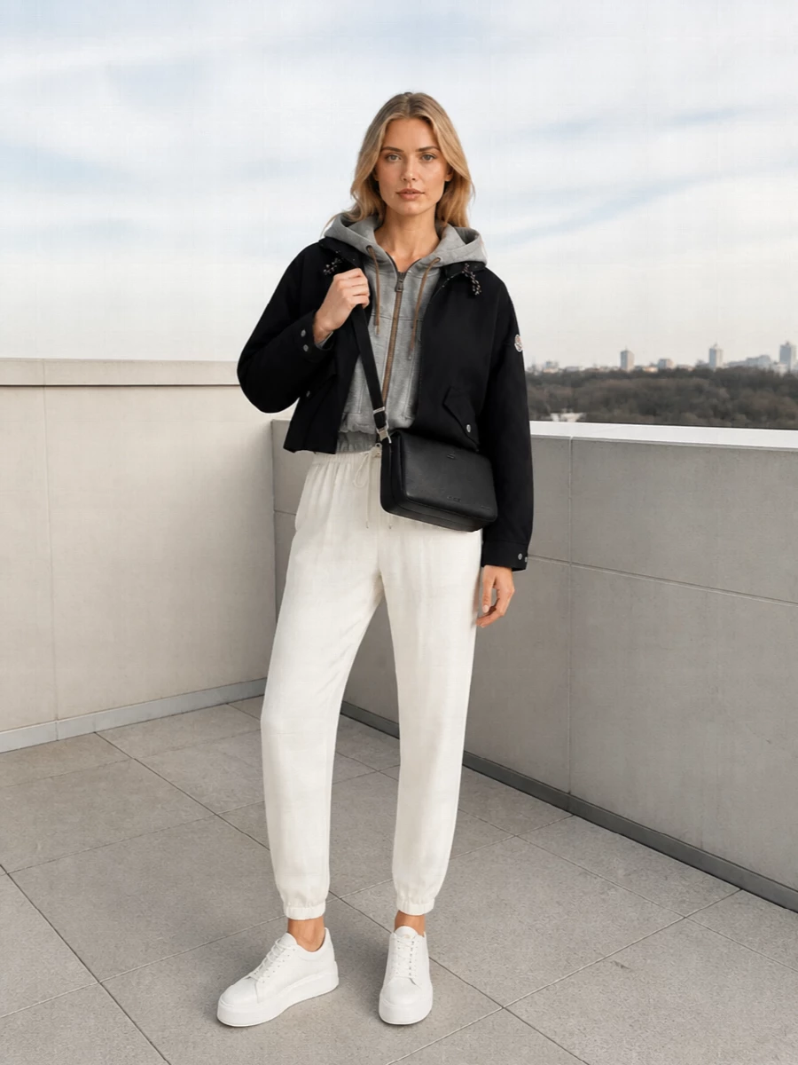 I am building around the Moncler cropped bomber with a coordinated top and bottom rather than a dress so the layered hood and jogger combination can fully express the elevated athleisure story. The Brunello Cucinelli cropped hoodie and ivory Fabiana Filippi joggers keep the proportions relaxed but controlled, while off-white Woolrich sneakers and a sleek Max Mara crossbody hold everything in a quietly luxurious, travel-ready register. The result is a black-and-soft-neutral palette that feels modern, technical and polished without slipping into overt streetwear or formality.