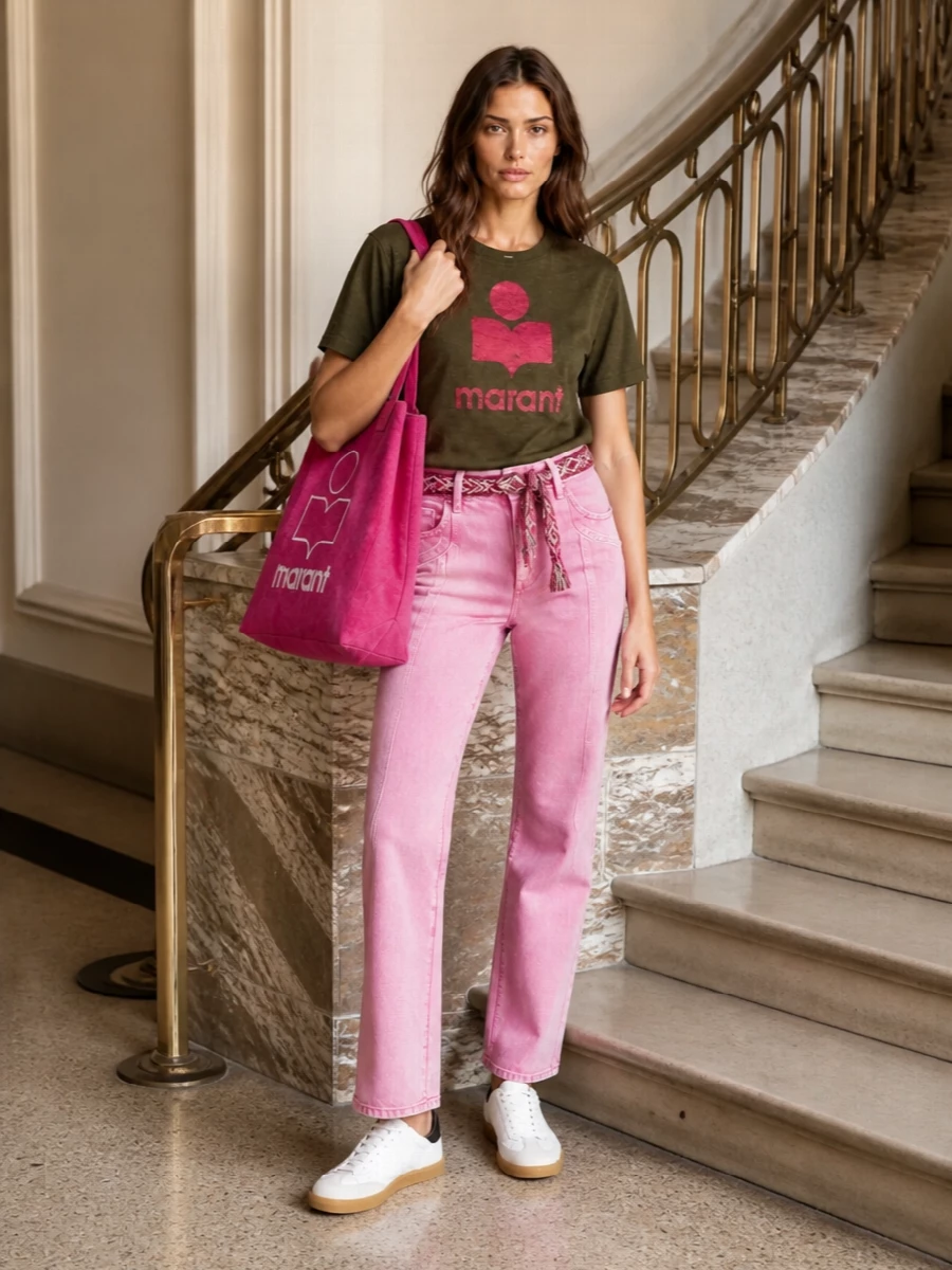 Olive logo cotton meets washed bubblegum denim for a fresh, colour-popped take on Parisian streetwear. A woven waist belt pulls the silhouette together, while crisp white sneakers and a bright logo tote keep it grounded for real life. Wear it for city days when you want relaxed ease with a confident hit of colour.