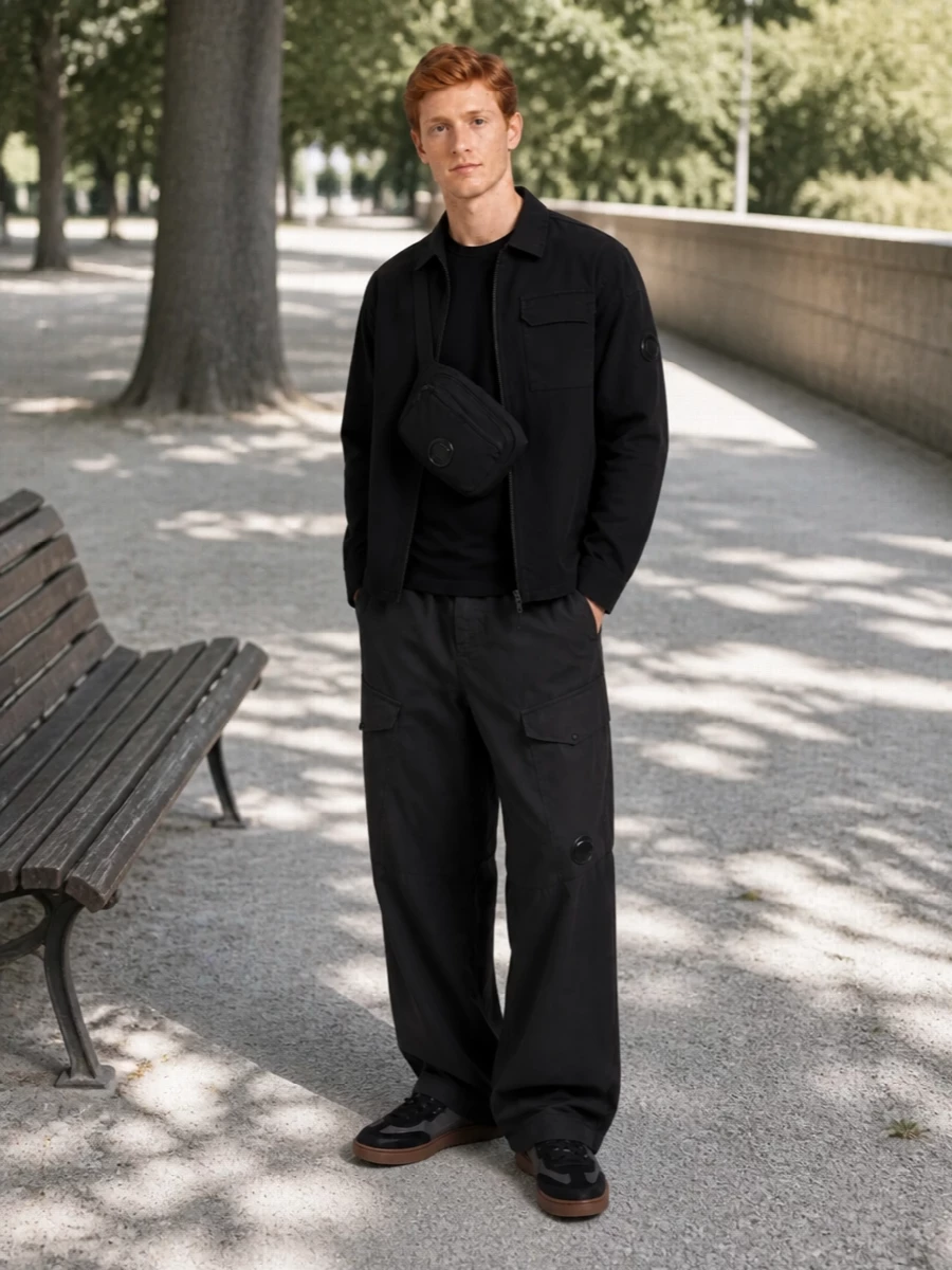 A fully monochrome C.P. Company uniform built around clean technical layers and a relaxed cargo silhouette. The wide-leg trouser and raglan crew add volume and structure, while the dark court sneaker and compact crossbody keep everything grounded and functional. It reads as modern city gear with quiet, coherent detailing from head to toe.