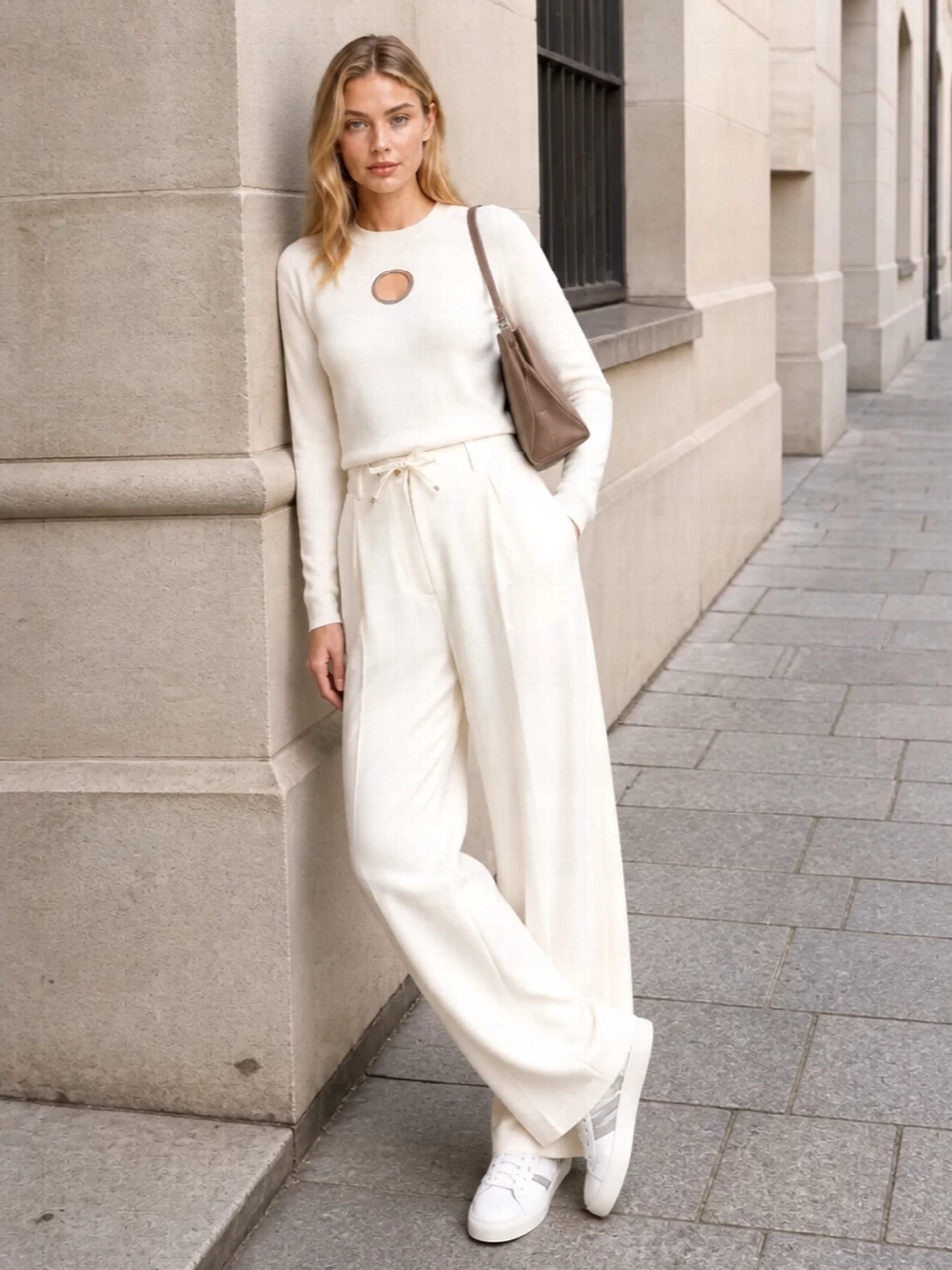 This look builds a tonal ivory column with Moncler’s fluid wide-leg trousers and the contemporary cut-out knit, keeping the silhouette clean yet subtly architectural. Off-white Moncler sneakers ground it with relaxed polish, while the taupe Balenciaga shoulder bag adds a soft, refined contrast that makes the ensemble feel city-ready and quietly luxurious for FW days in motion.