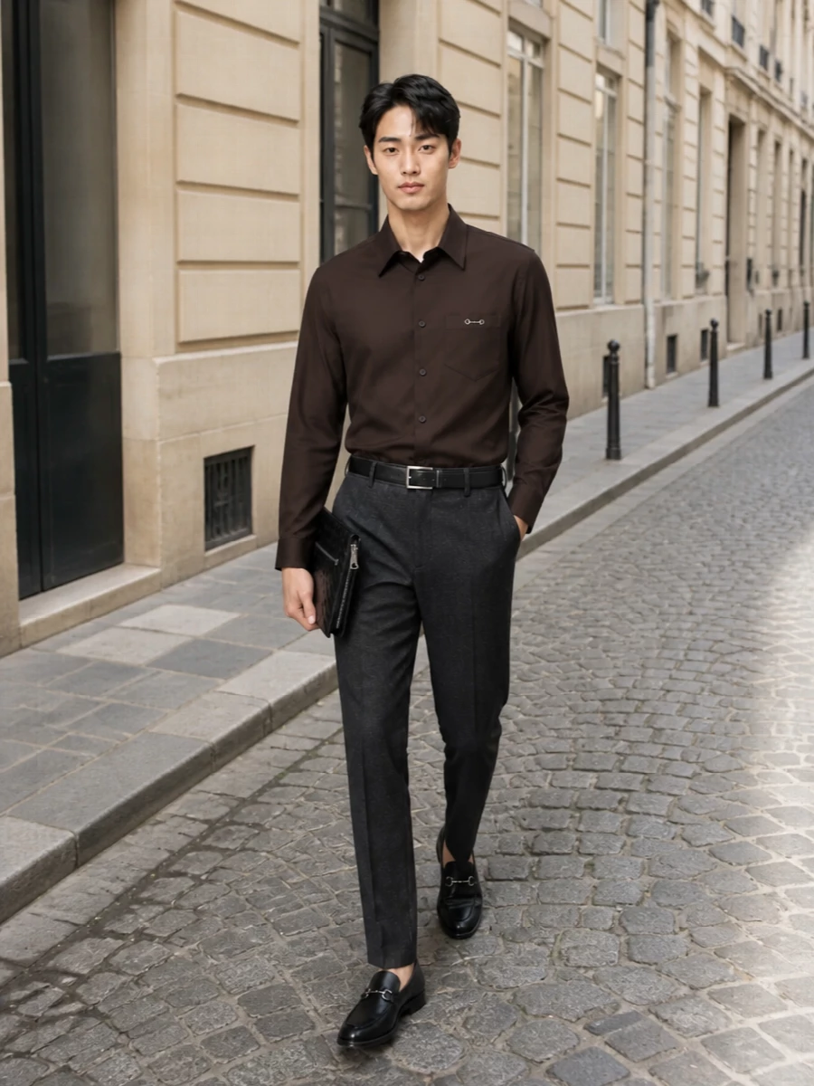Charcoal herringbone trousers are grounded with a sharply cut chocolate Gucci shirt for a rich, tonal FW palette that still feels restrained. Black horsebit loafers and a precise black belt keep the line clean and formal, while the slim Bottega wristlet adds a discreet note of craft without disturbing the minimalist silhouette. The result is a quietly powerful office-to-evening look that reads polished from every angle.