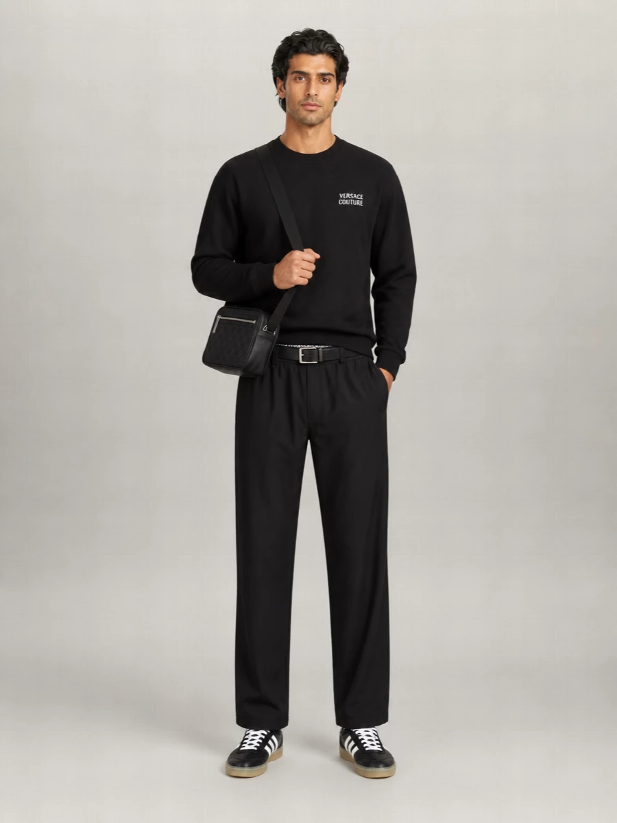 Versace’s branded jogger-style pant is paired with a discreet black logo sweatshirt for a clean, monochrome street take that lets the Greca waistband stay the hero detail. Black Adidas terrace sneakers keep the energy athletic yet slim, grounding the outfit without extra bulk. A tonal Gucci crossbody and low-profile web belt bring just enough polish for city days without breaking the relaxed mood.